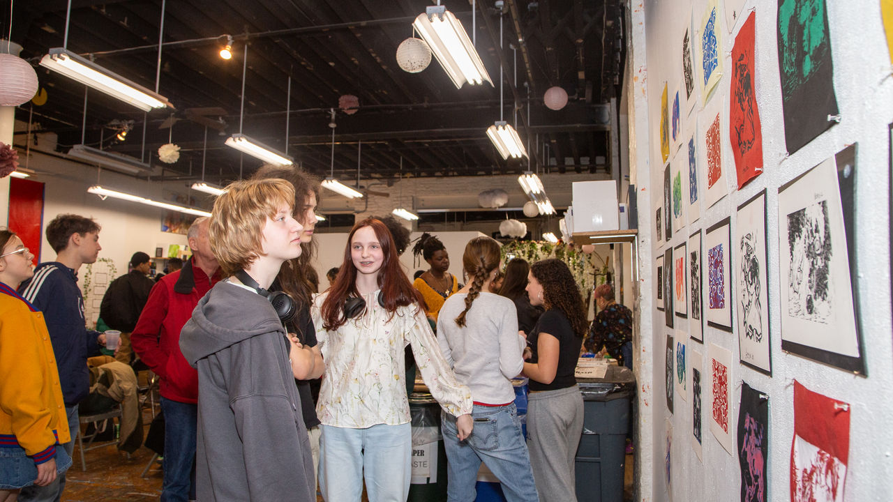 Students and friends looking at art displayed on the wall 