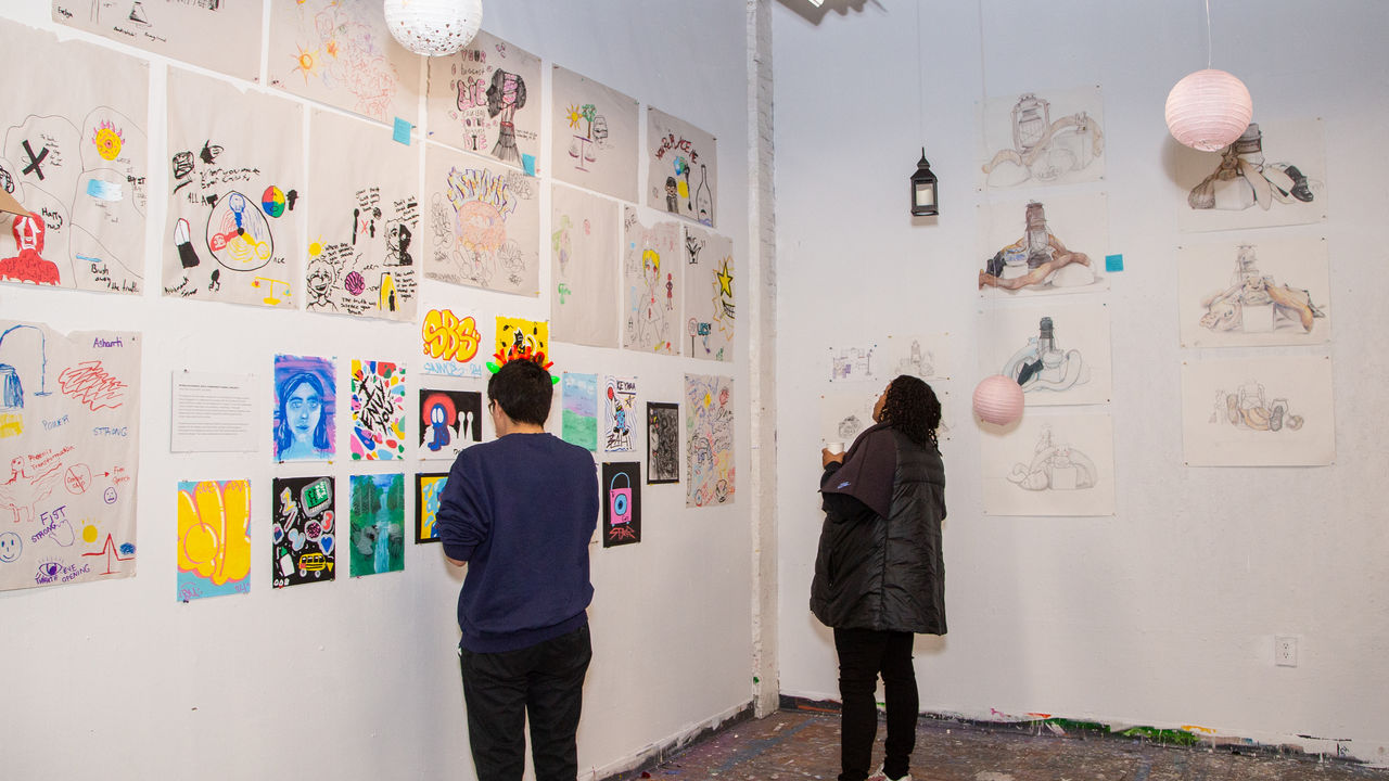 Two people looking at artwork displayed on the wall