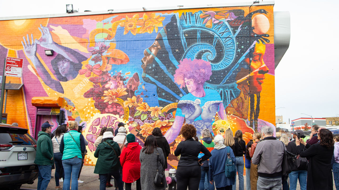 Group of people looking at mural that is on the wall