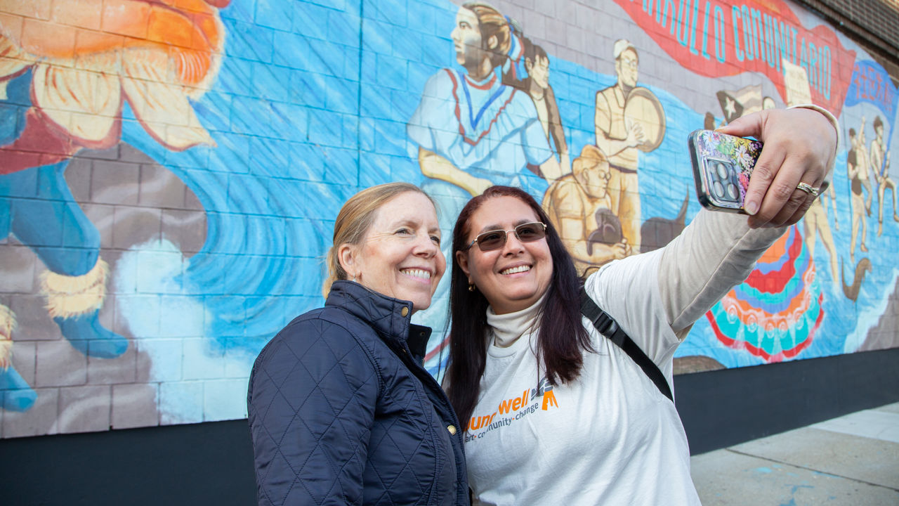 Two people taking a selfie in front of a mural 
