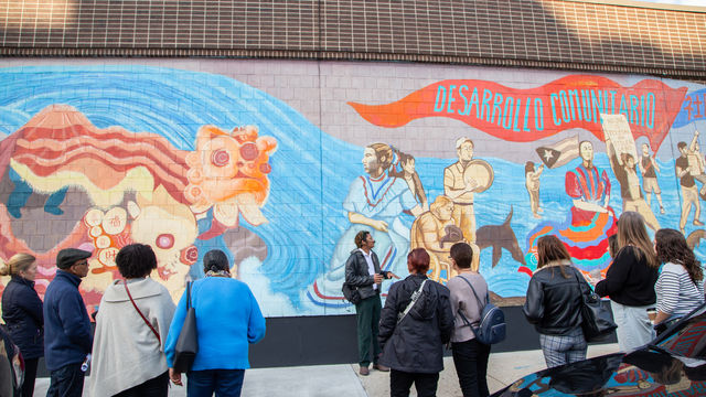 People listening to a presenter talk about the mural in front of them 