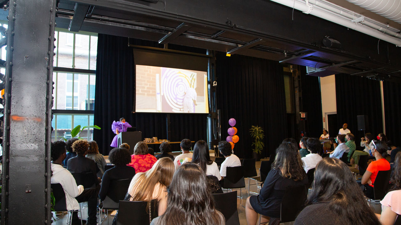 Group of people listening to presenter on stage