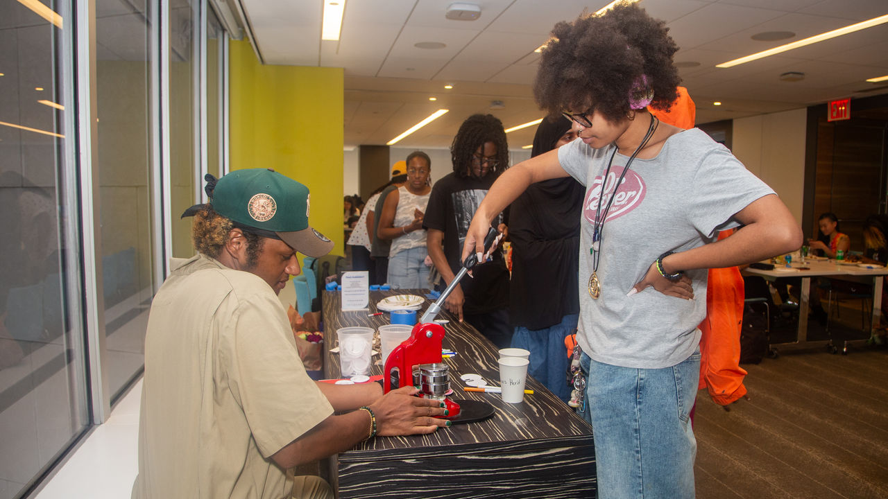 Teacher helping student with pin-making machine 