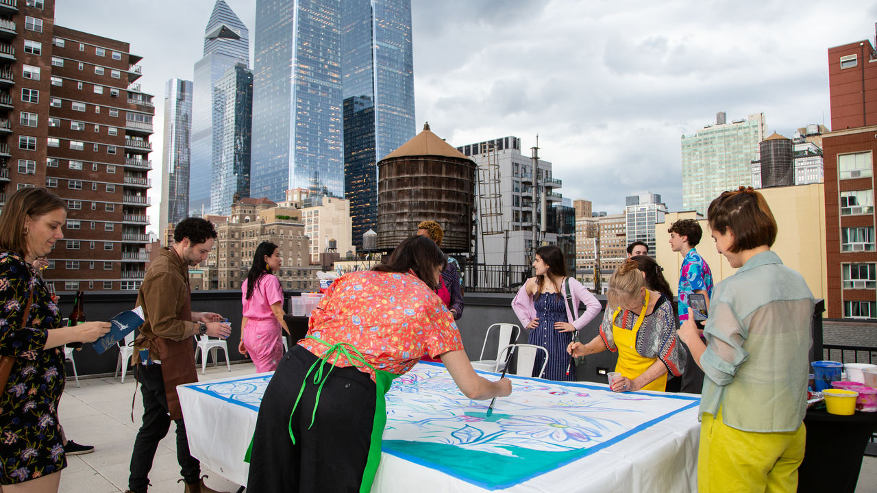 Group of people painting a mural with skyline in background