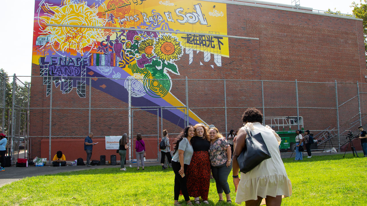 Group of three taking a photo in front of the finished mural. 