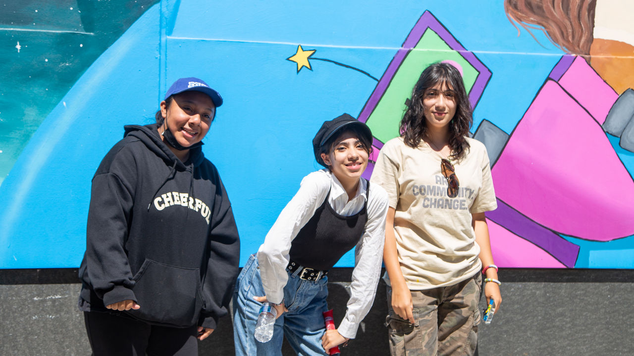 Group of three posing with their artwork. 