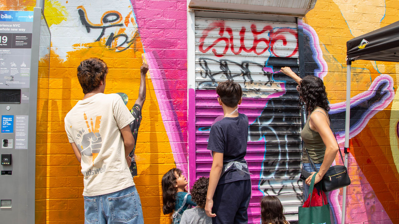 Group of people and kids painting the mural on a wall. 