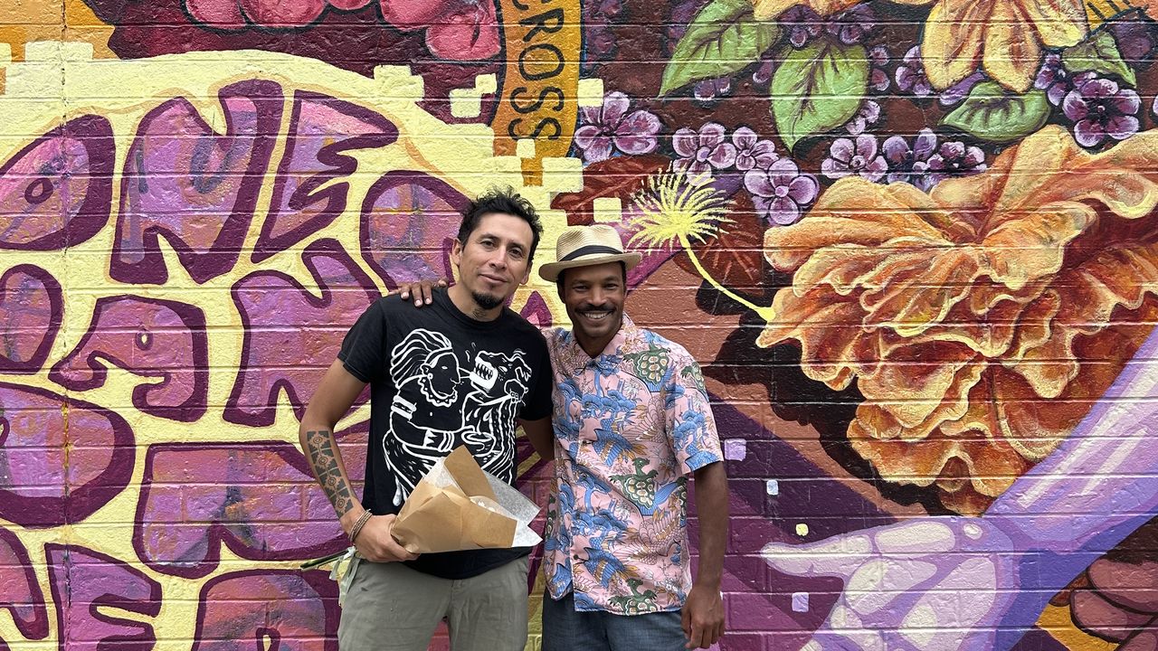 Two teachers posing in front of artwork 