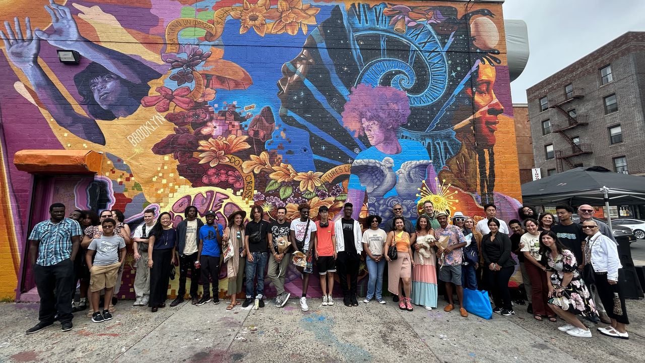 Big group of people posing in front of completed mural. 
