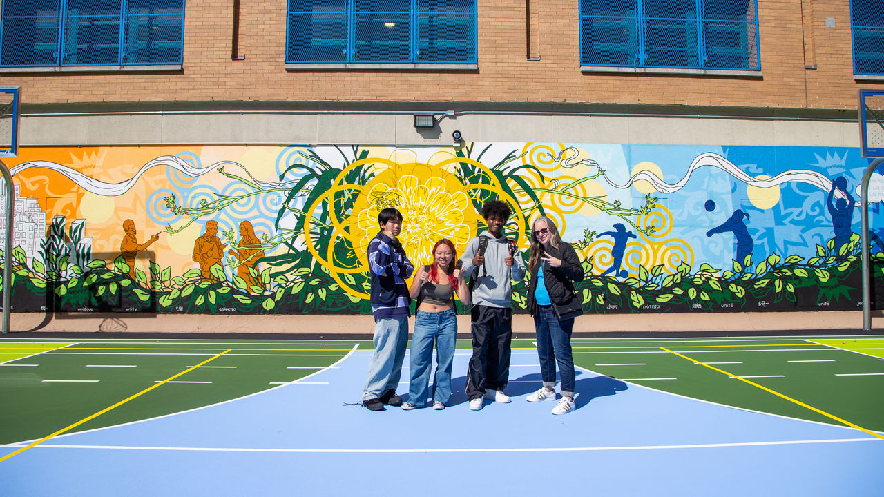 Group photo of teacher and a few students in front of completed mural.