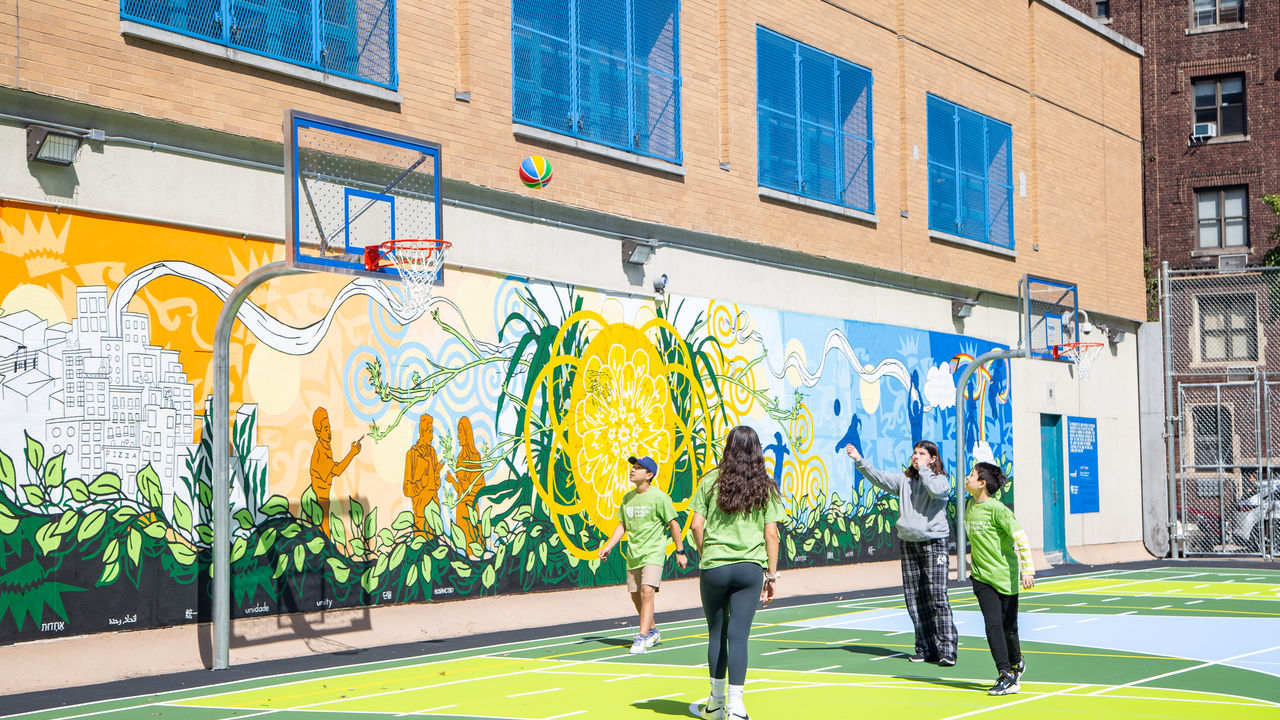 Kids playing basketball with new mural in the background. 