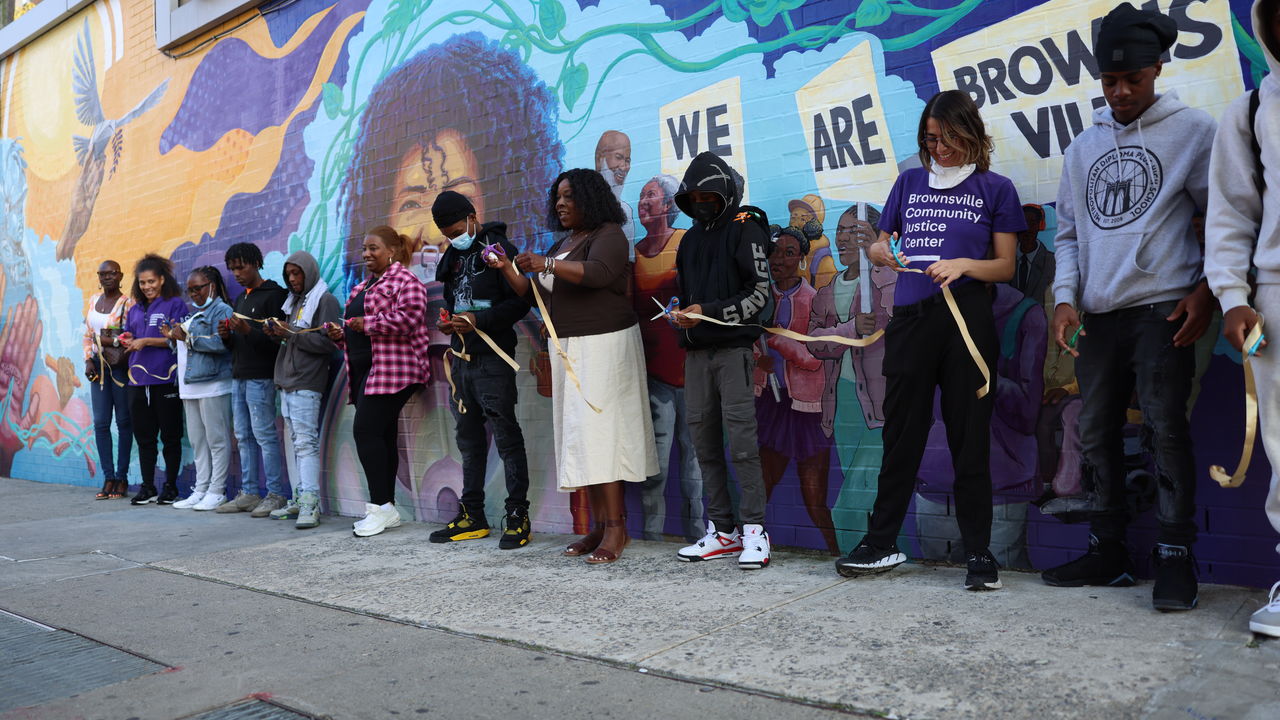 Photo of group of people in front of new mural doing a ribbon cutting ceremony. 