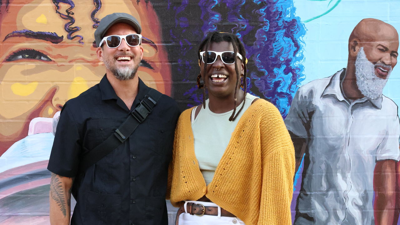 Two teachers posing in front of their artwork 
