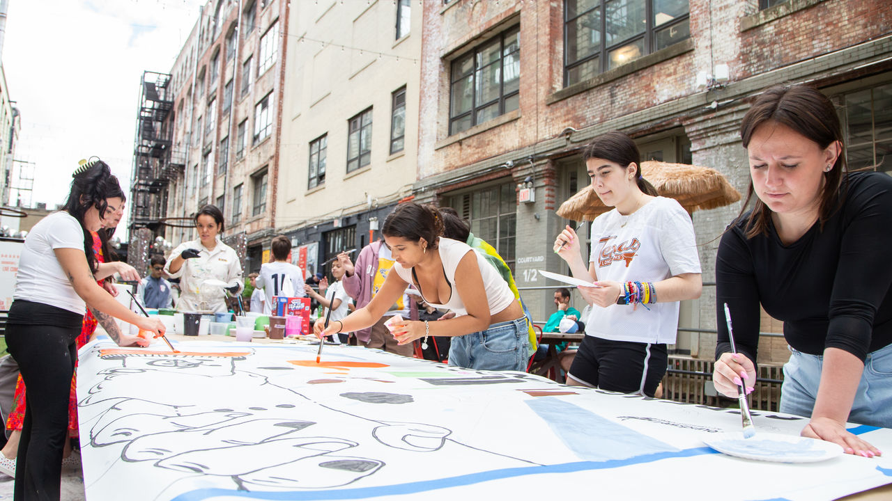 Close up photo of people around a table painting a mural. 