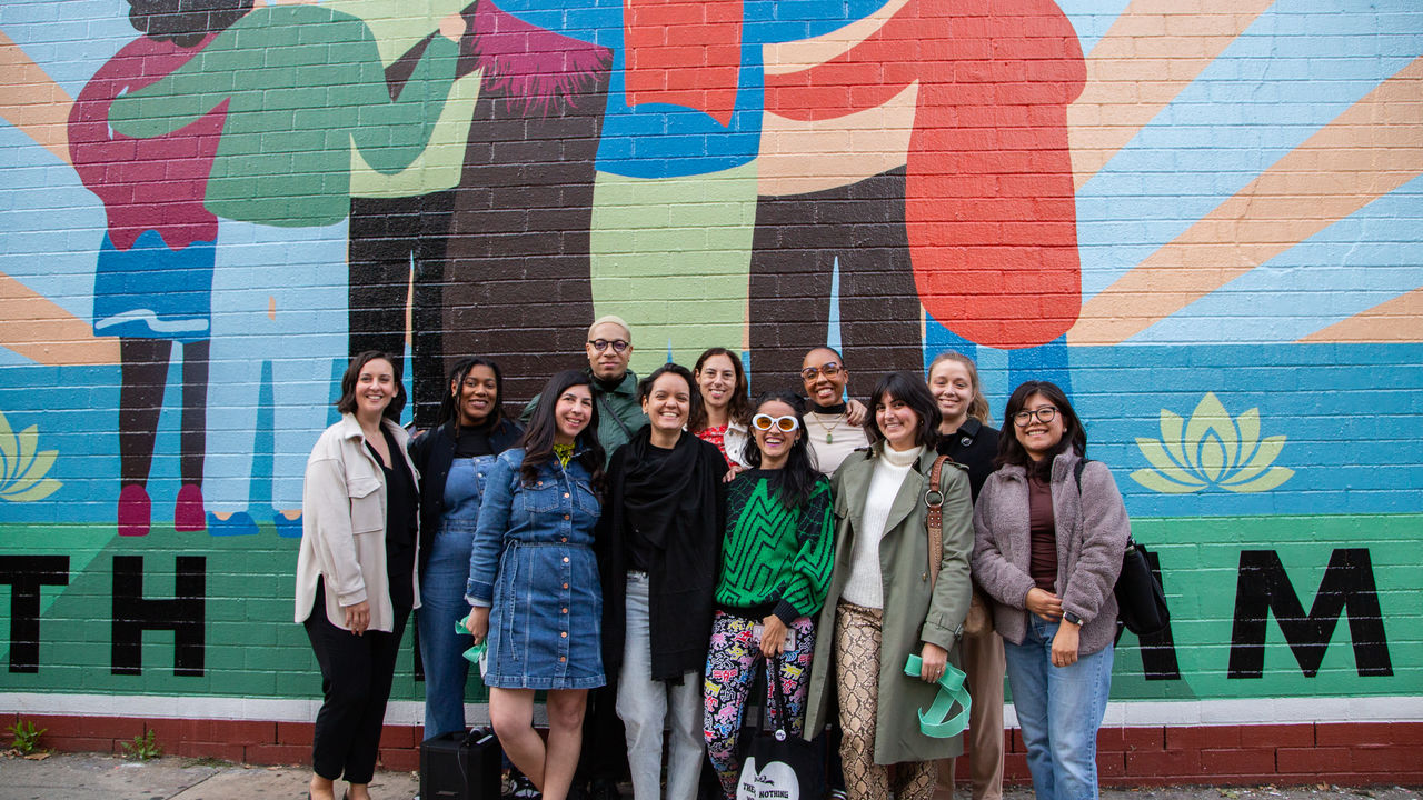 Group photo of people posing in front of a mural. 