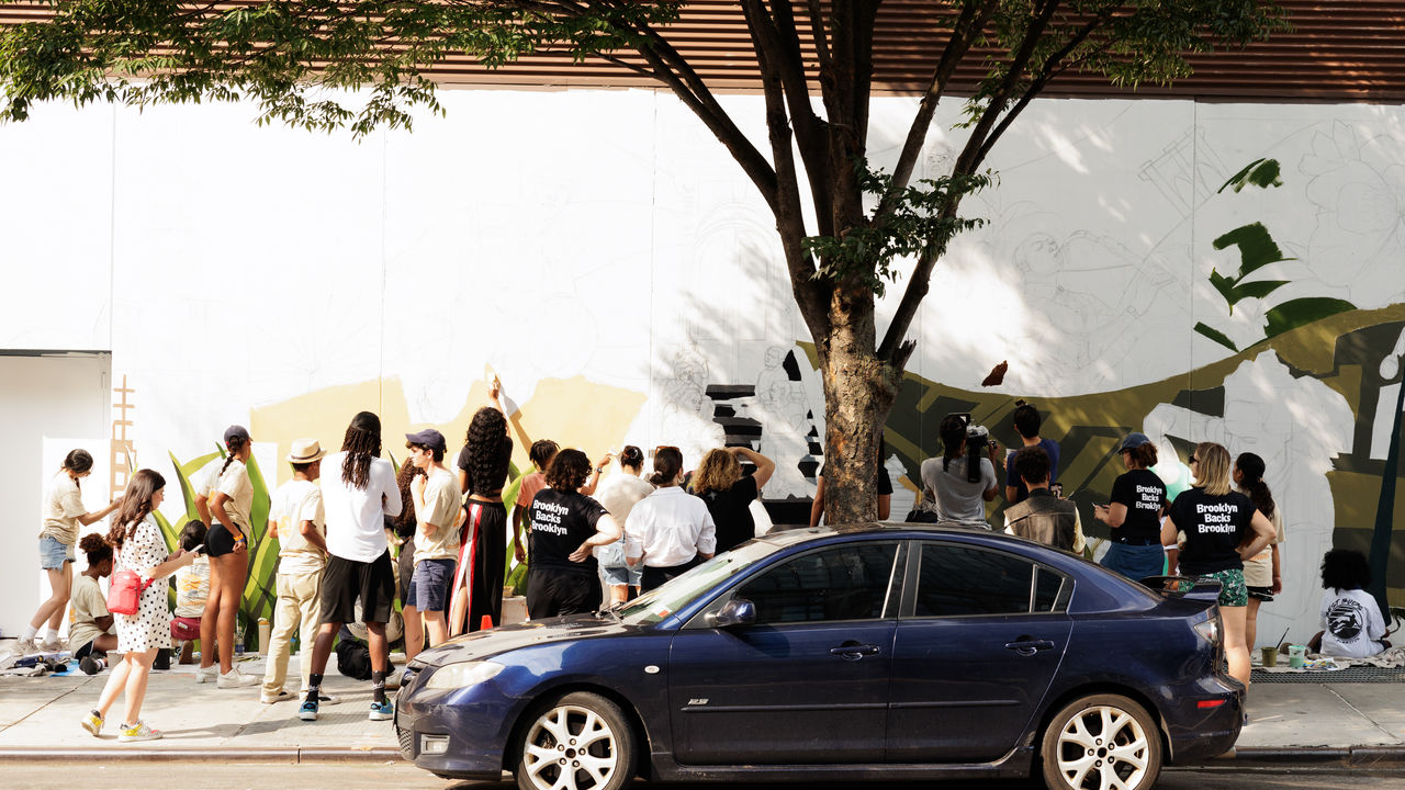 Wide photo of people painting a mural onto a wall