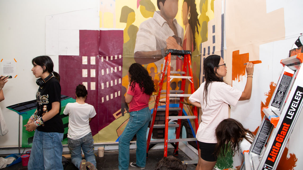 Room of people painting a mural on parachute cloth 