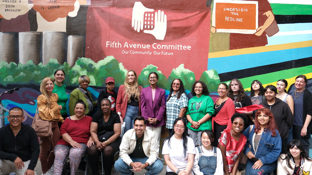 Group photo of people posing in front of a mural