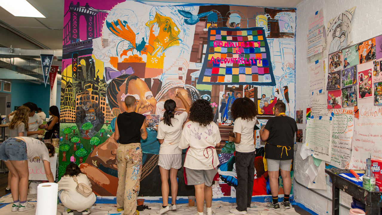 A group of people painting a mural on the wall 