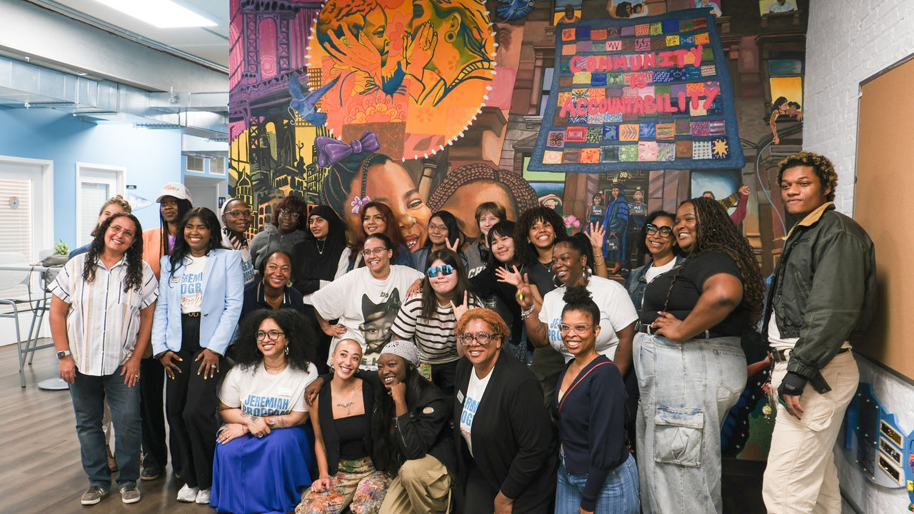 Group of people posing in front of a mural