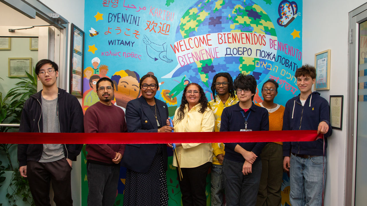 A group of people posing in front of a mural doing a mural dedication