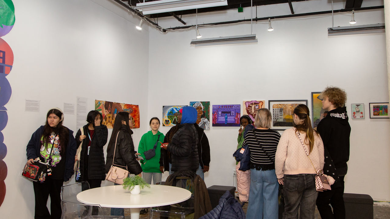 People looking at various artwork hanging on the wall