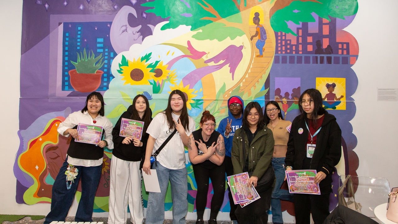 Group of students and teacher posing in front of finished mural 