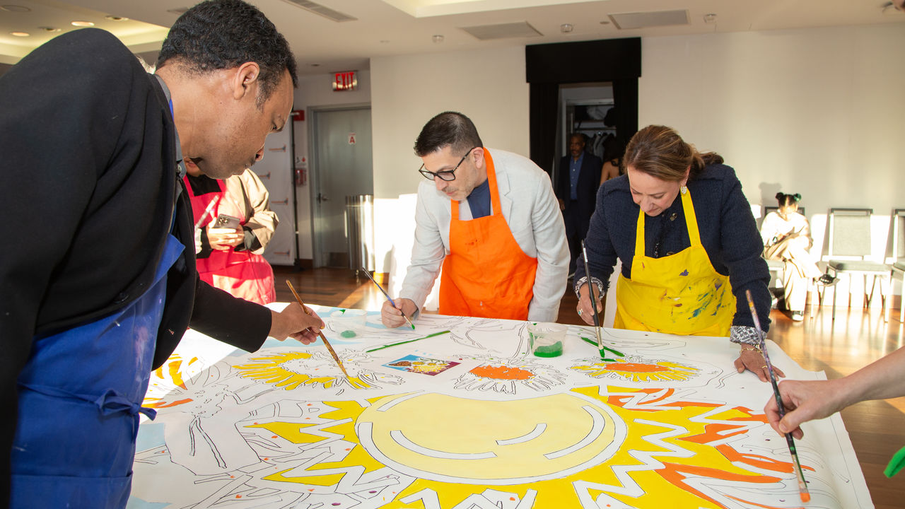 Three people painting a canvas 